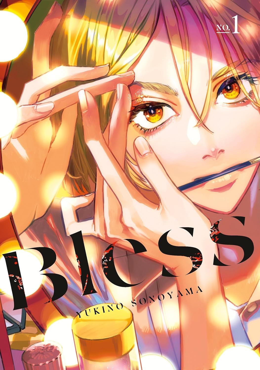 Portada del primer tomo del manga: una persona rubia de ojos ámbar, con un pincel entre los labios, se lleva la mano a la cara ante un espejo de camerino rodeado de bombillas